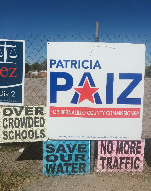 Protest signs surrounding a Patricia Paiz campaign sign on Bride Blvd. These signs reference how the Santolina Master Plan would allegedly stretch South Valley resources thin. Photo by Christina Rodriguez / NM News Port