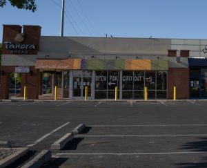 panera store with empty parking lot and open for takeout sign